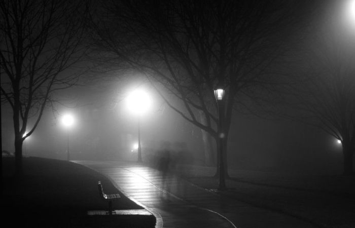 an image of rain and blurred figures in a park at night